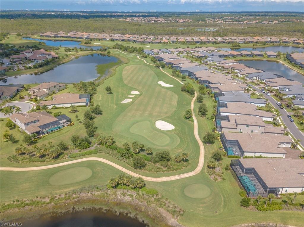 Aerial view of property and surrounding area featuring a nearby body of water, nearby suburban area, and a local golf course
