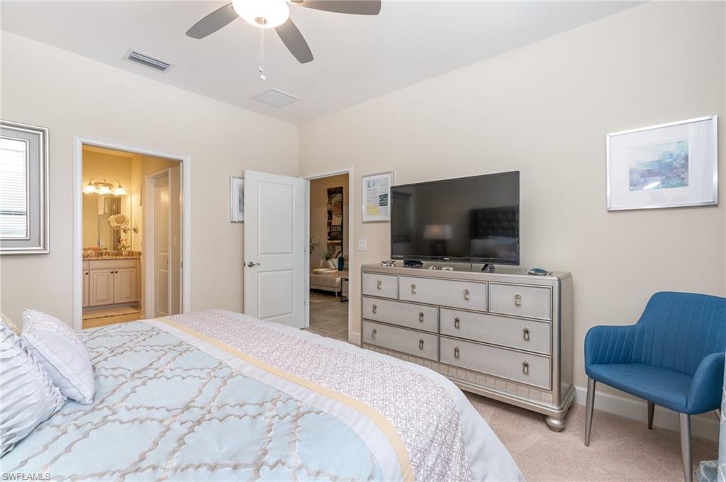 Bedroom with light colored carpet, ceiling fan, and ensuite bath