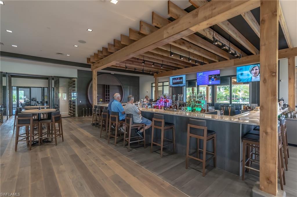 Community bar area with dark wood-style floors, light stone countertops, and recessed lighting