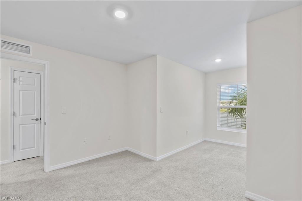 Empty room with light colored carpet and recessed lighting