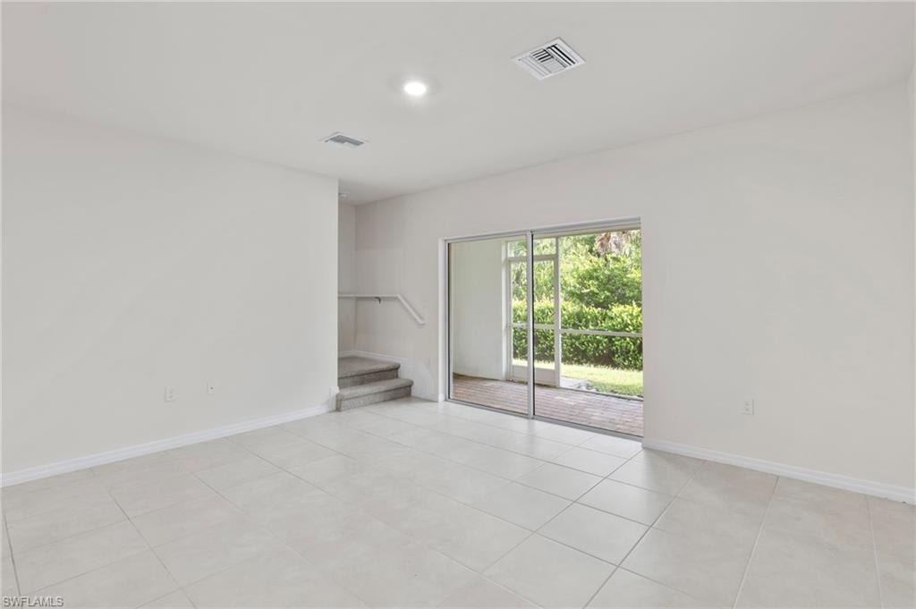 Empty room with light tile patterned floors and stairway