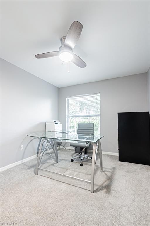 Home office/bedroom featuring light colored carpet and a ceiling fan