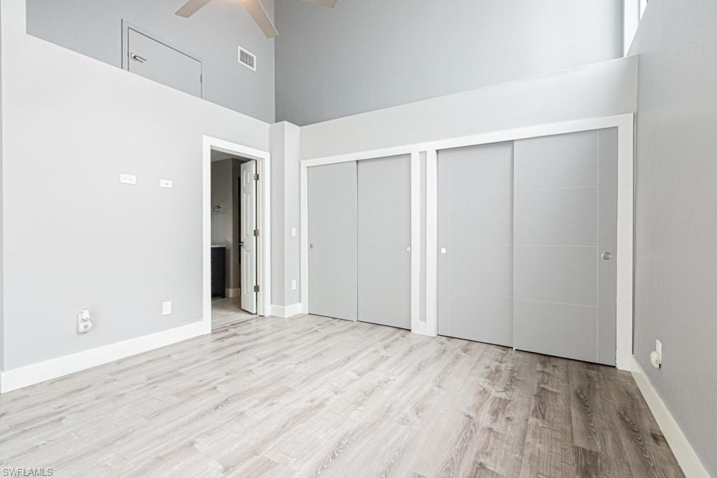 Unfurnished bedroom featuring two closets, a high ceiling, light wood finished floors, and ceiling fan