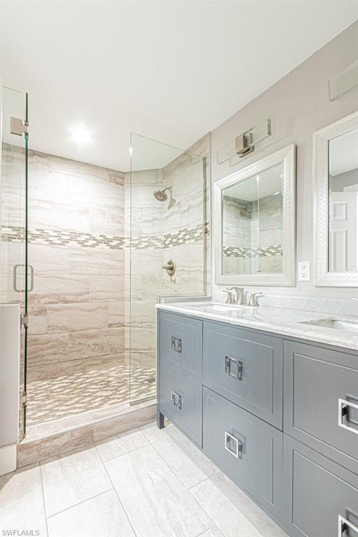 Bathroom featuring double vanity, a shower stall, and light tile patterned floors