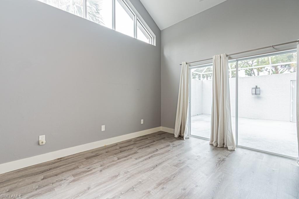 Empty room featuring light wood-style floors and high vaulted ceiling