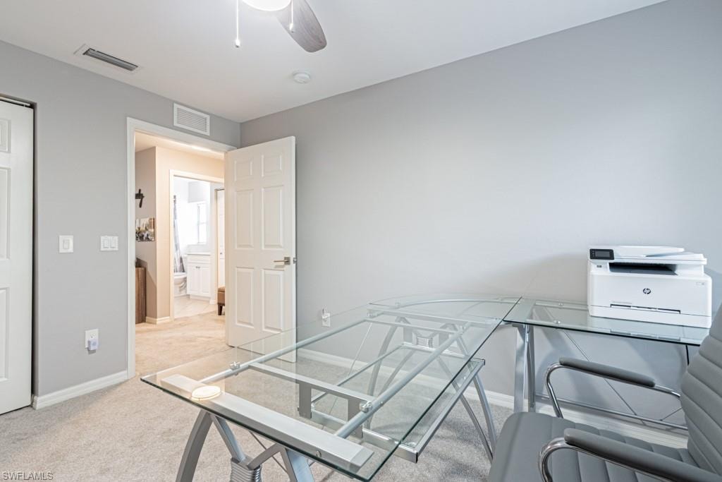 Office/bedroom space with light carpet and ceiling fan