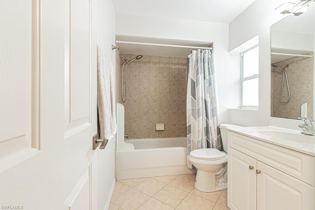 Full bathroom with shower / bath combination with curtain, vanity, and light tile patterned floors