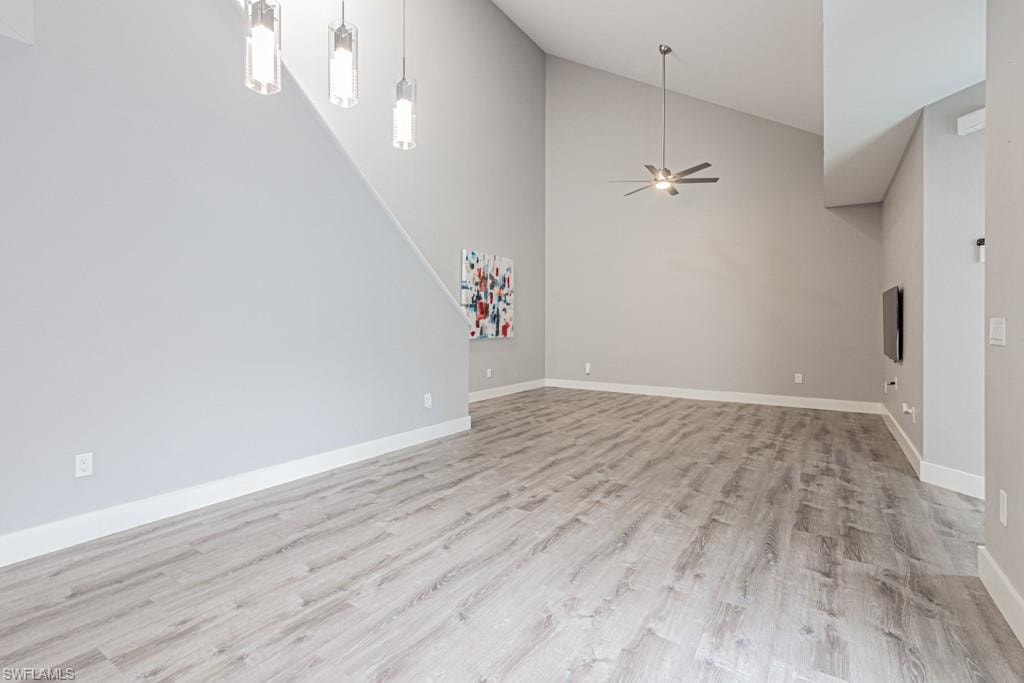 Unfurnished living room with high vaulted ceiling, light wood finished floors, and a ceiling fan