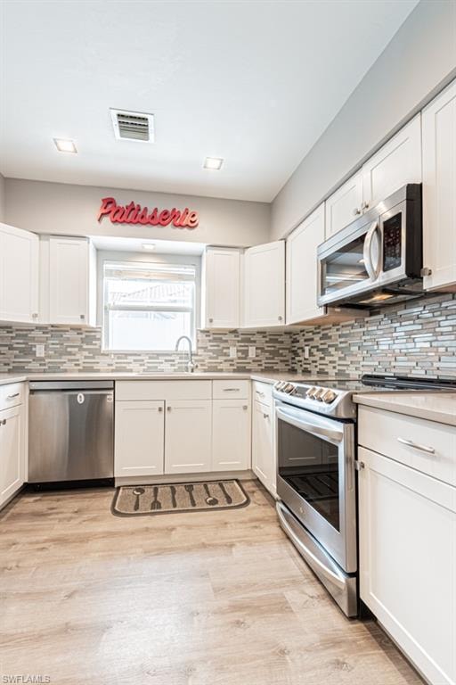 Kitchen featuring white cabinetry, stainless steel appliances, and tasteful backsplash