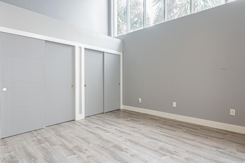 Unfurnished bedroom featuring two large closets, light wood finished floors, and a towering ceiling
