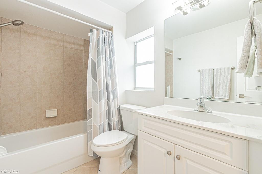 Bathroom with shower / bath combination with curtain, light tile patterned floors, and vanity