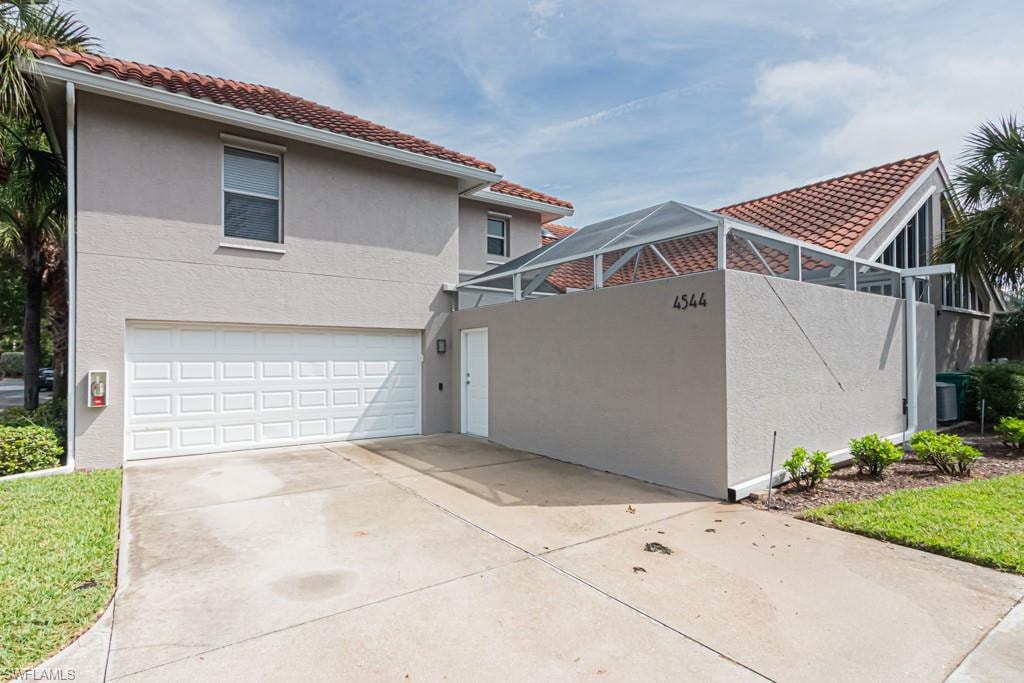 View of side of home featuring a tiled roof, stucco siding, driveway, and a garage
