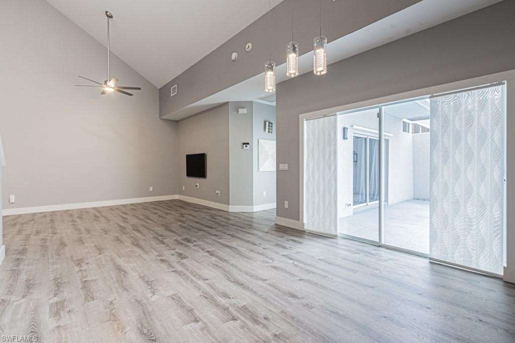 Unfurnished living room featuring light wood finished floors, high vaulted ceiling, and ceiling fan