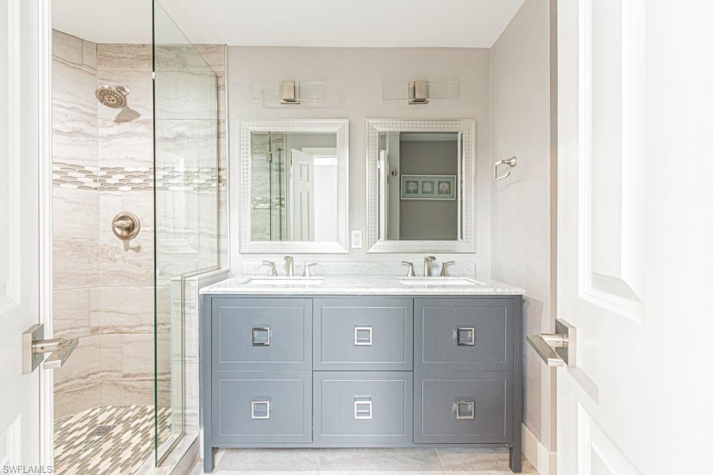 Bathroom with a stall shower, double vanity, and light tile patterned floors
