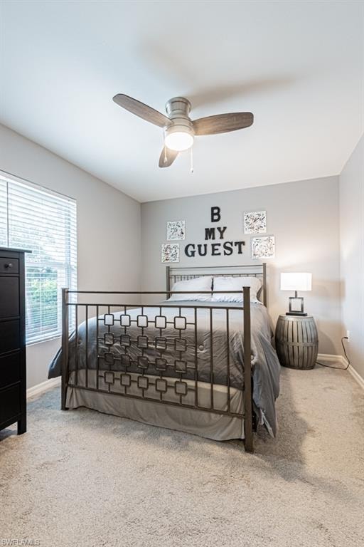 Carpeted bedroom with baseboards and a ceiling fan