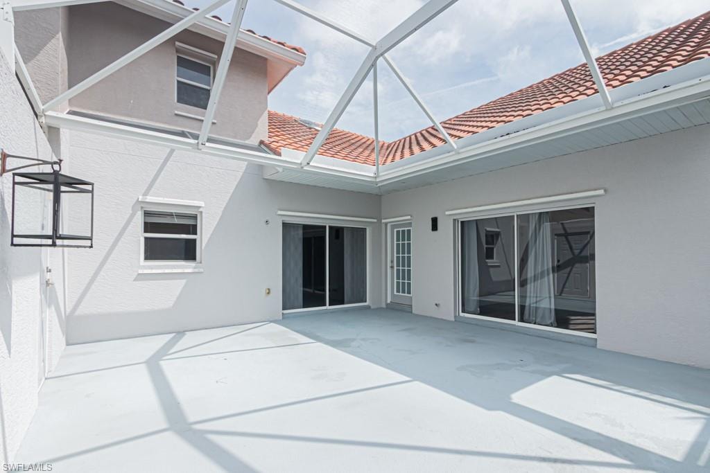 Rear view of house with a sunroom, a patio, a tiled roof, and stucco siding