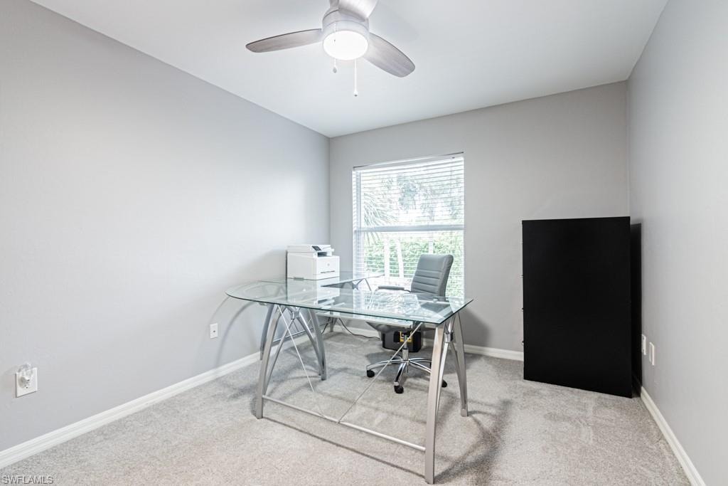 Office/bedroom area featuring a walk in closet, carpet and a ceiling fan