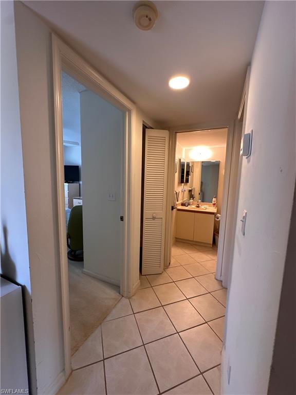 Hallway featuring light tile patterned floors and light carpet