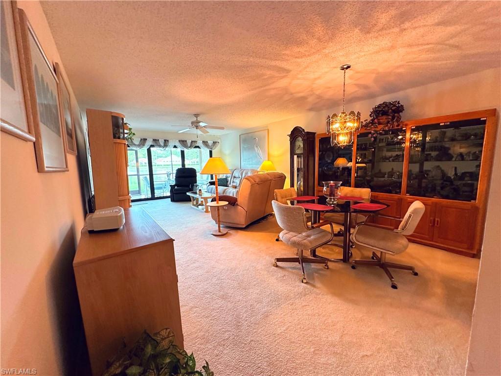 Dining space featuring carpet flooring, a textured ceiling, a chandelier, and ceiling fan