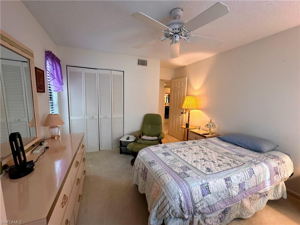 Bedroom with light carpet,  a ceiling fan, and multiple closets