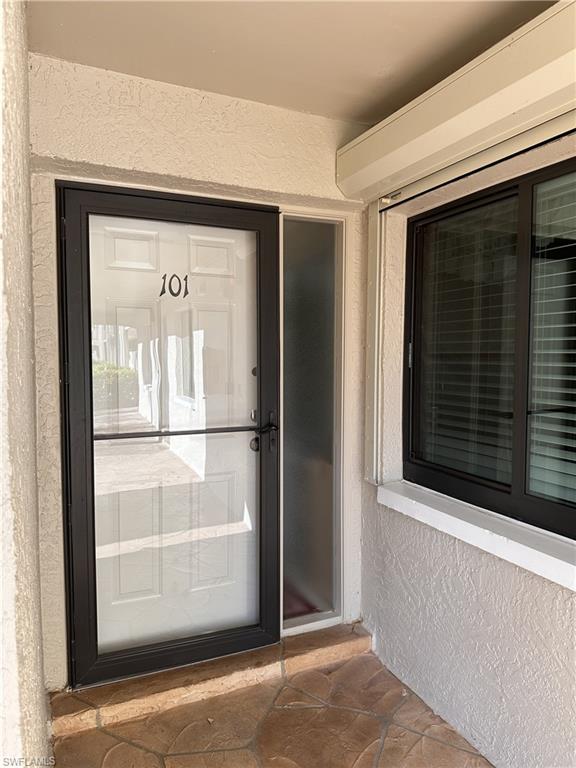 Property entrance impact door with stucco siding and a wall mounted AC