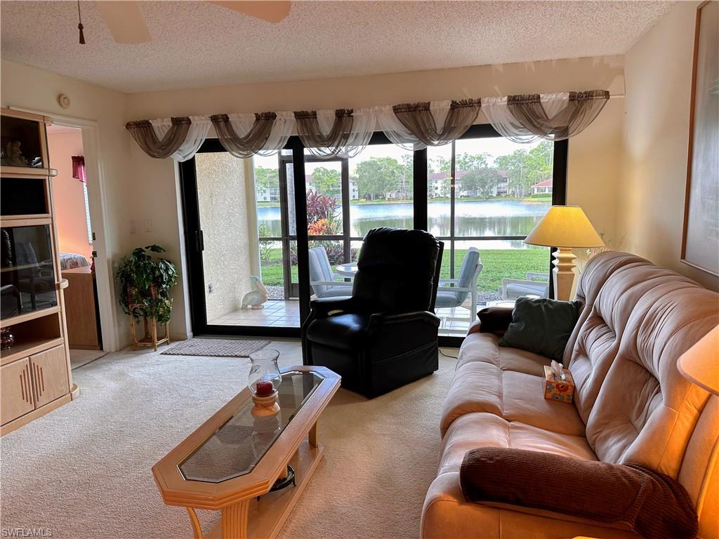 Living room with carpet floors, a water view, and ceiling fan