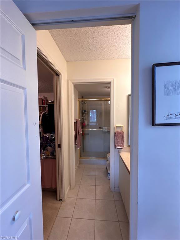 Bathroom with a stall shower, light tile patterned floors, vanity, a walk in closet