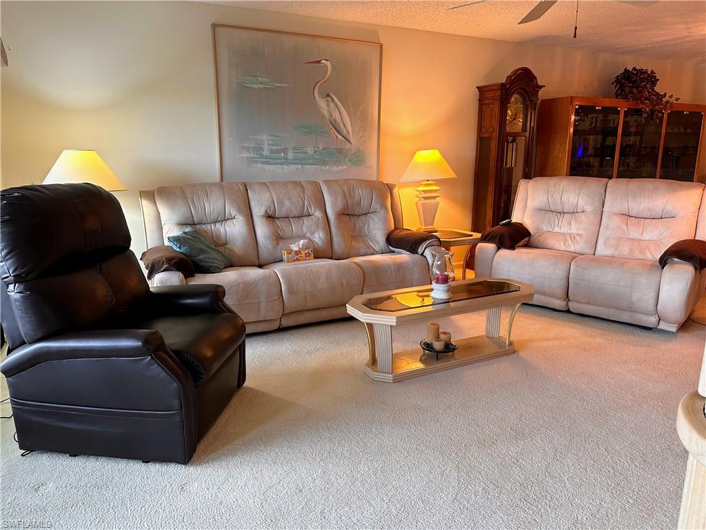 Carpeted living room featuring ceiling fan