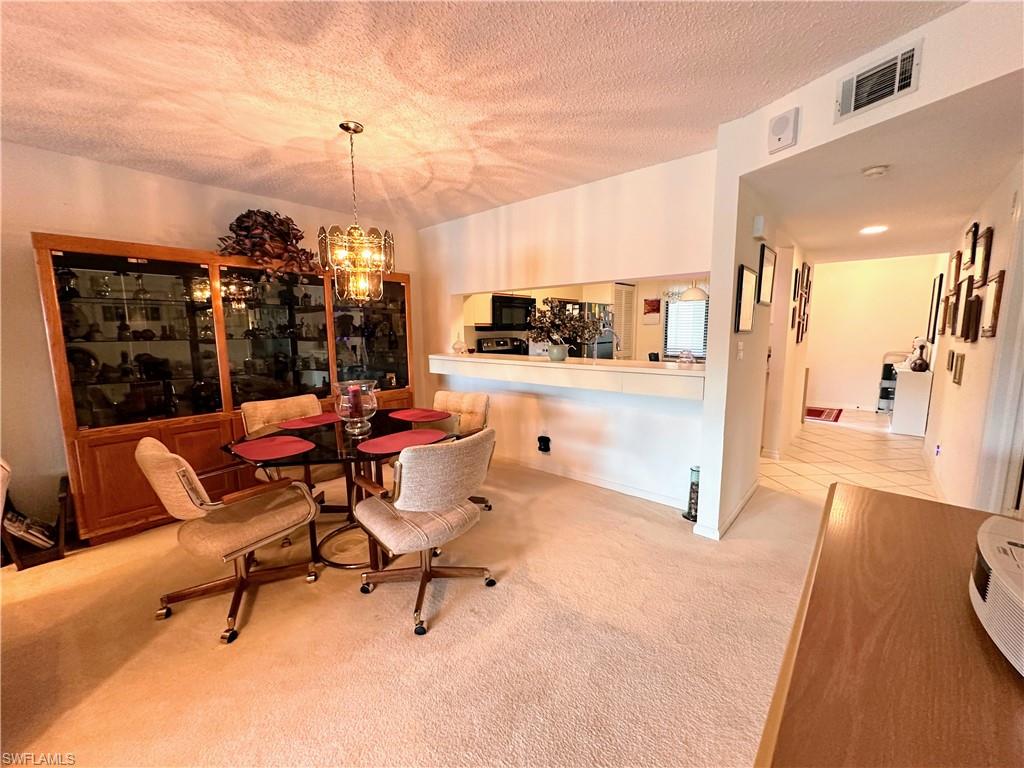 Dining space featuring light colored carpet, and a chandelier