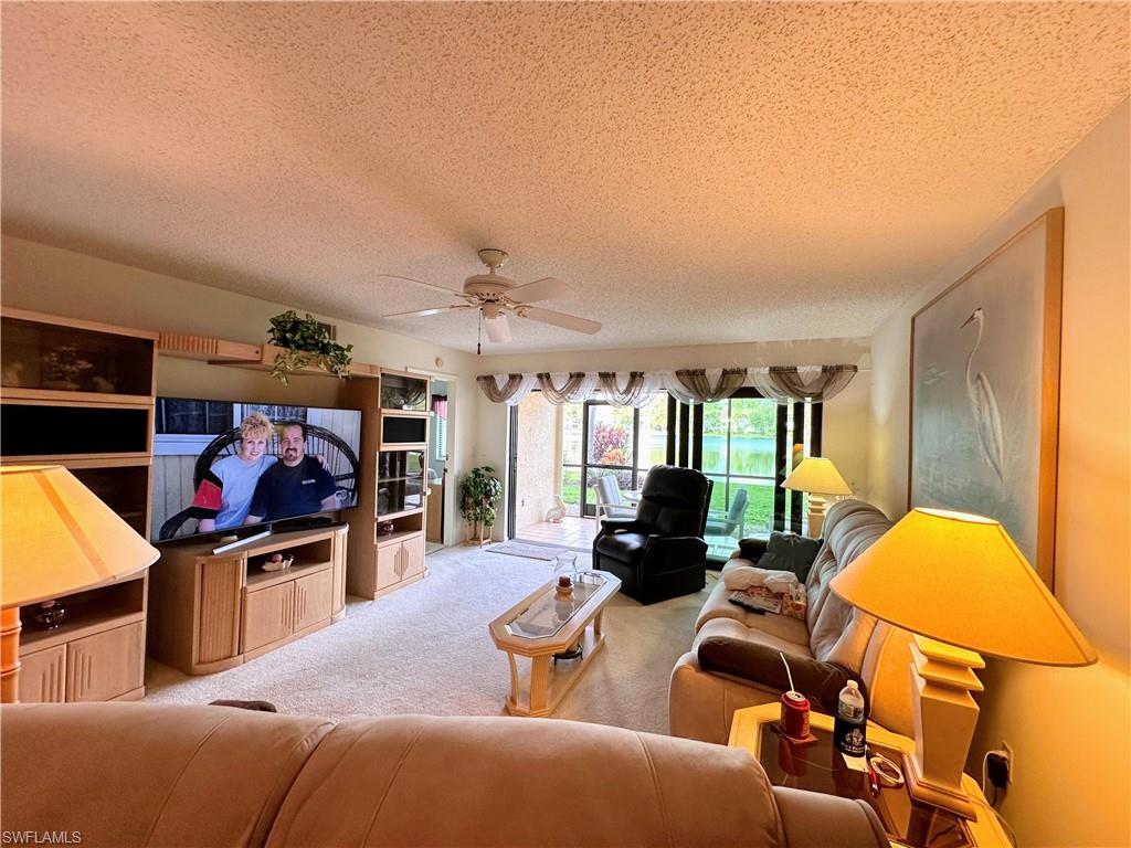 Carpeted living room with a ceiling fan