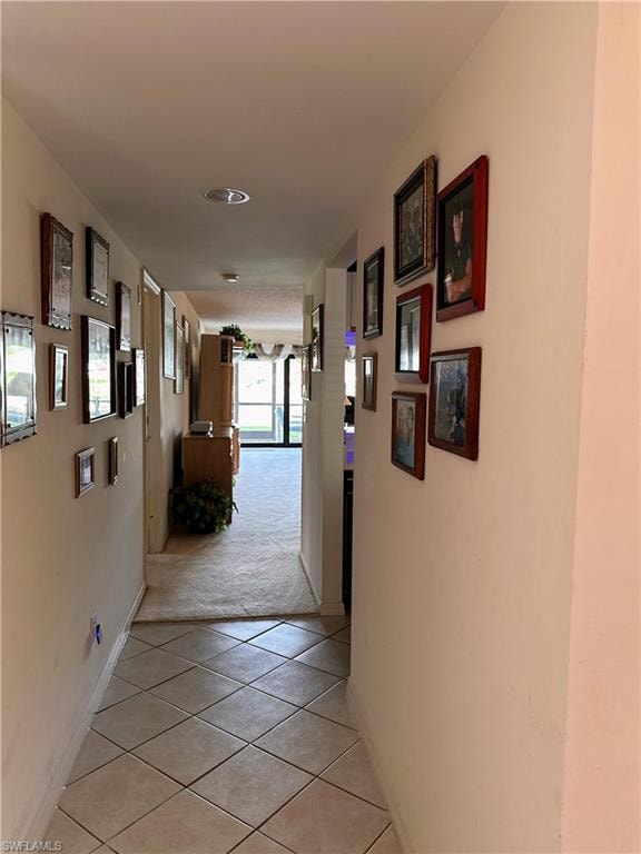 Hallway with light tile patterned flooring and baseboards