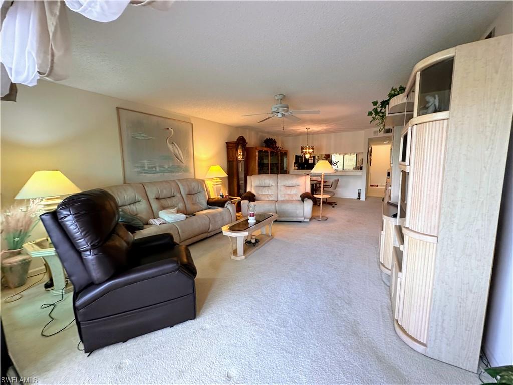 Carpeted living room with ceiling fan