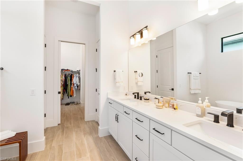 Full bathroom featuring double vanity, wood finish floors, and a spacious closet