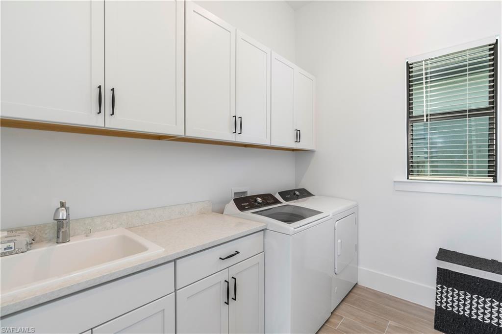 Laundry room featuring wood tiled floors, cabinet space, and washing machine and clothes dryer
