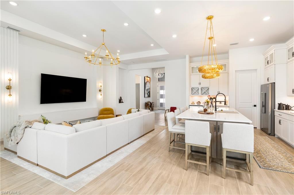Living room featuring a tray ceiling, recessed lighting, a chandelier, and wood finish floors