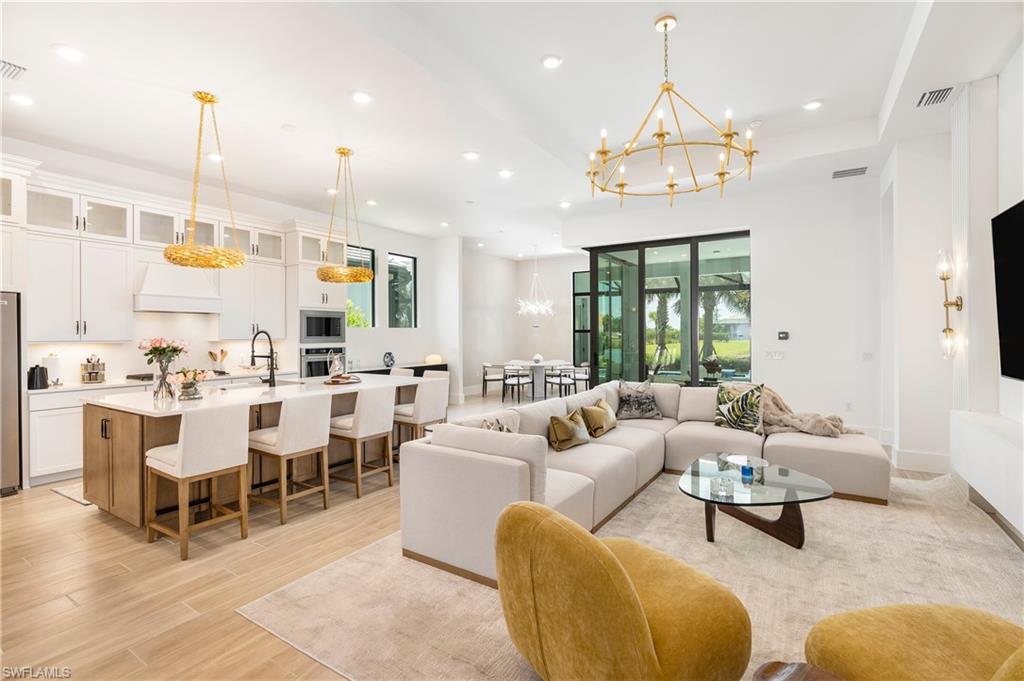 Living room with a chandelier, recessed lighting, light wood-style floors, and a raised ceiling