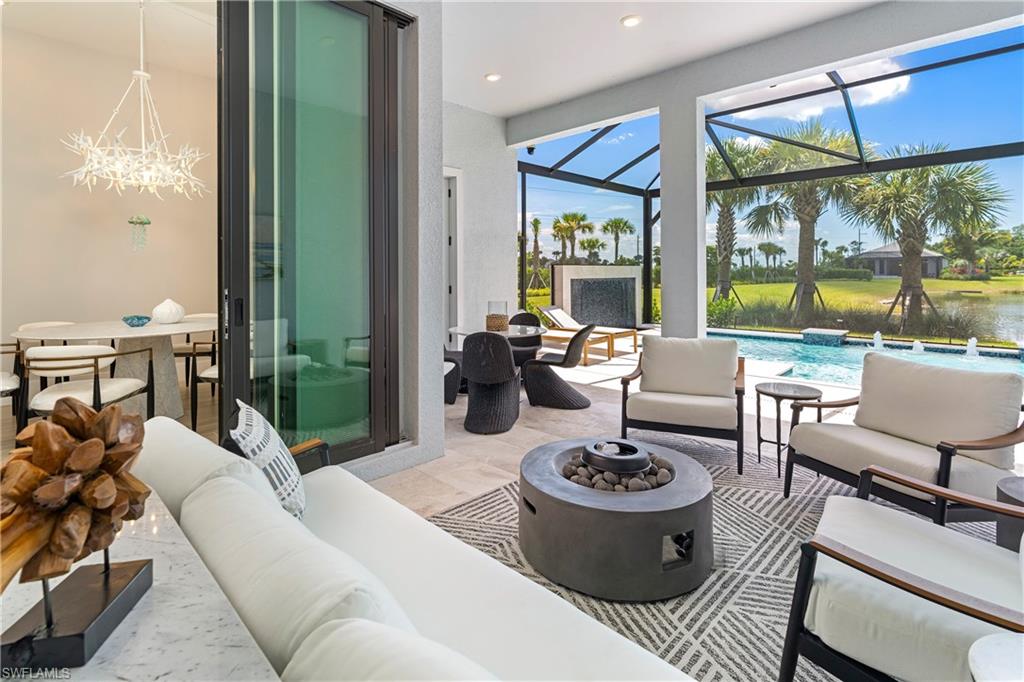 View of patio with a sunroom, an outdoor pool, an outdoor living space with a fire pit, and a lanai