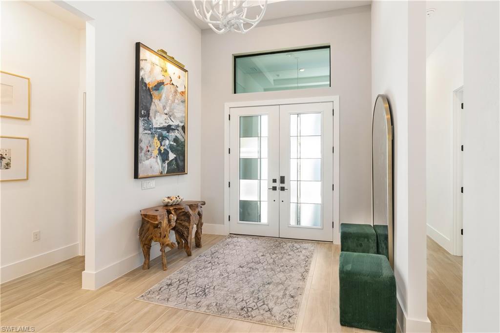 Entryway with french doors, light wood finished floors, and a high ceiling