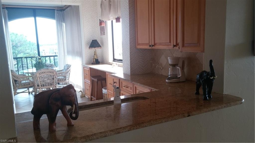 Kitchen with light stone countertops, healthy amount of natural light, backsplash, and tile patterned floors