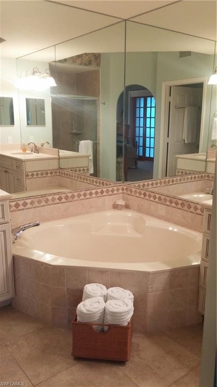 Full bath featuring a garden tub, light tile patterned floors, and vanity
