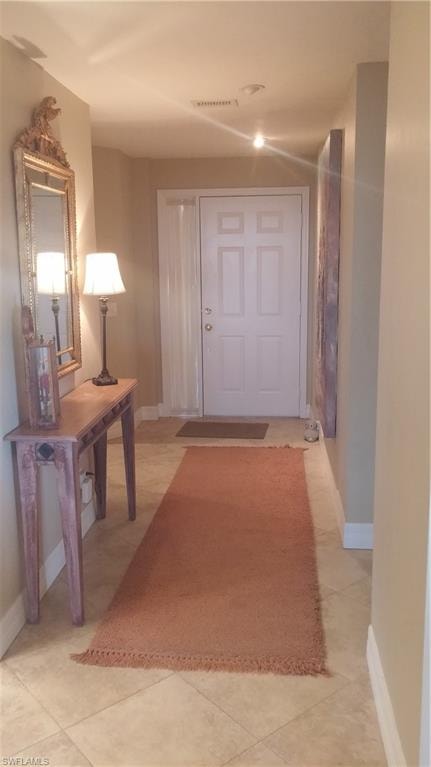 Hall featuring baseboards and light tile patterned flooring