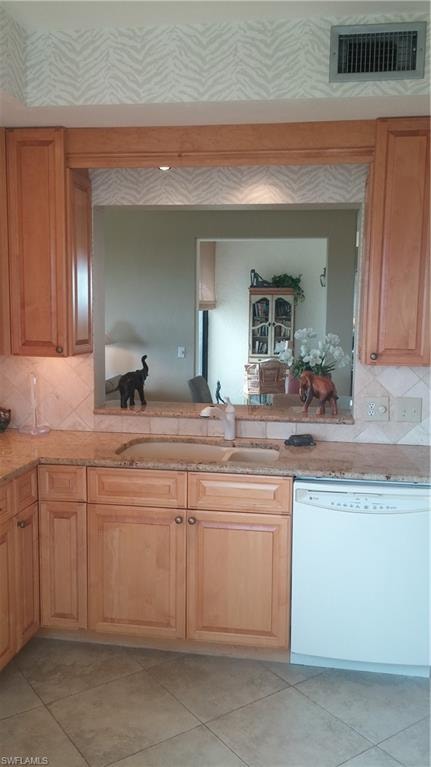 Kitchen featuring tasteful backsplash, dishwashing machine, light stone counters, and light tile patterned flooring