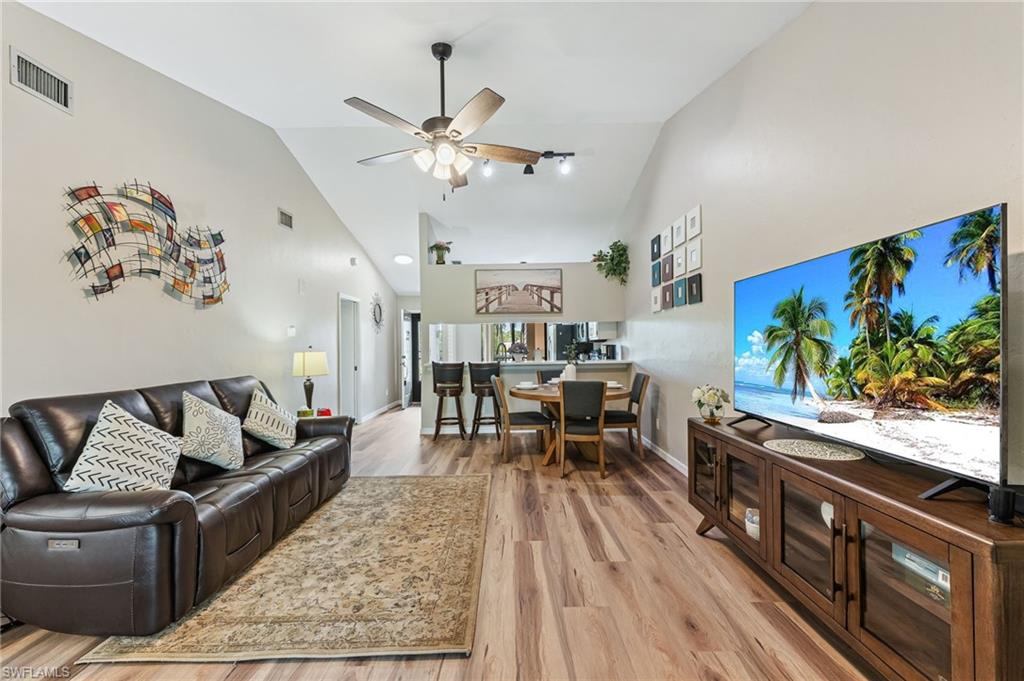 Living room featuring high vaulted ceiling, light wood-style floors, and a ceiling fan