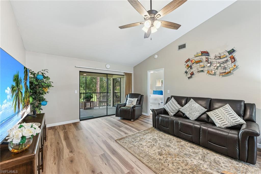 Living room with light wood-style flooring, high vaulted ceiling, and ceiling fan