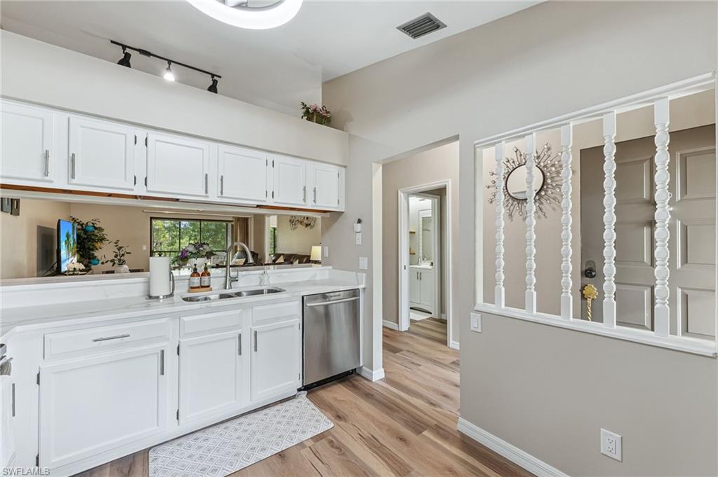 Kitchen featuring white cabinets, dishwasher, and light wood-style floors