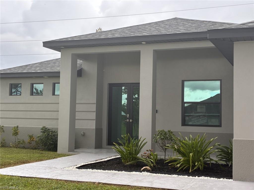 Doorway to property featuring a shingled roof, stucco on block, and french doors.