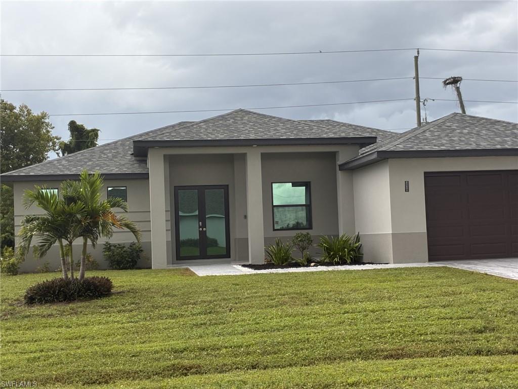Contemporary-style home featuring roof with shingles, stucco block, a front yard, and an attached garage