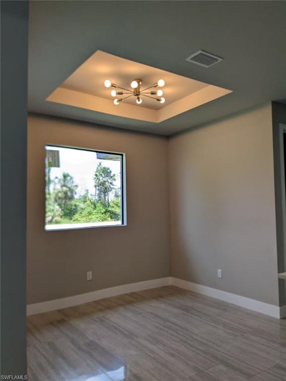 Dining room with a chandelier, a tray ceiling, and wood style porcelain floors.