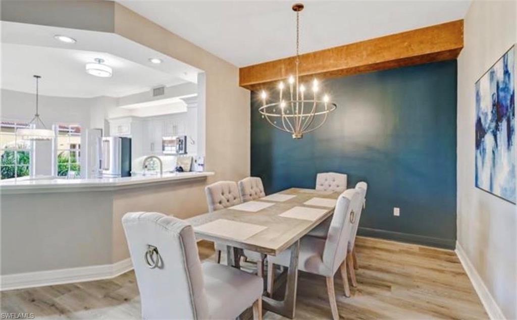 Dining space with a chandelier, light wood-style floors, beamed ceiling, and recessed lighting