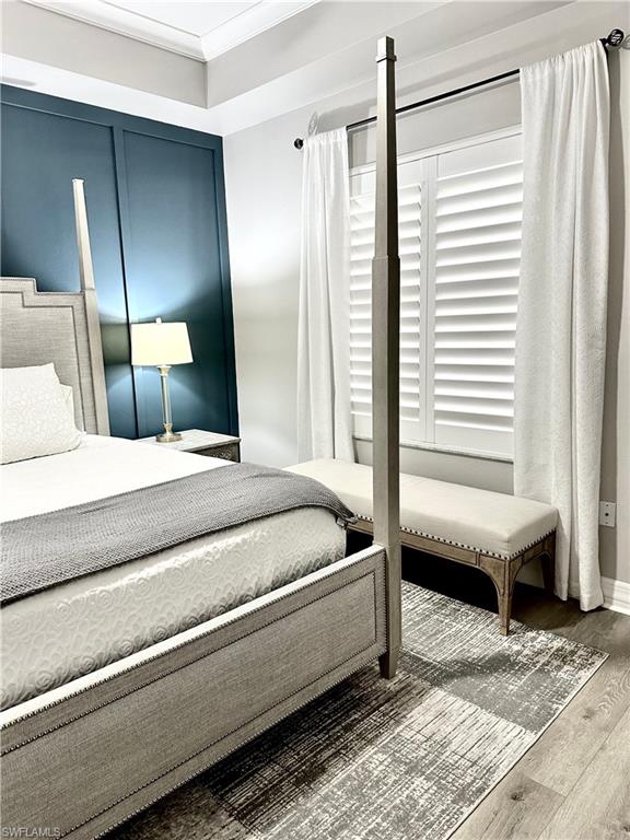 Bedroom with wood finished floors and crown molding